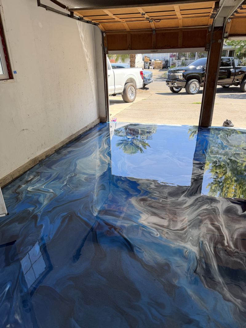 Blue metallic epoxy garage floor with open door view