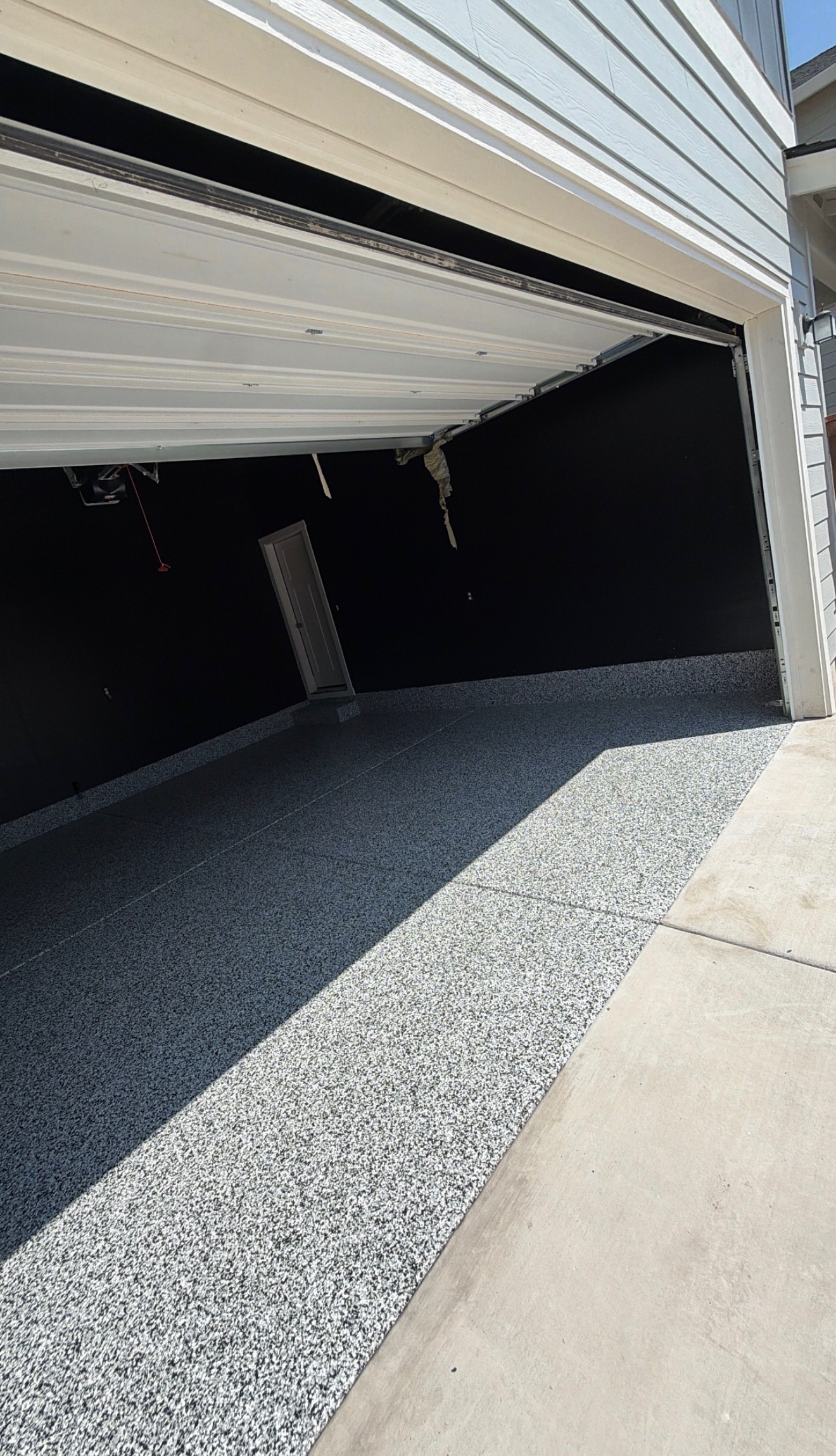 Gray and black flake epoxy garage floor viewed from the driveway