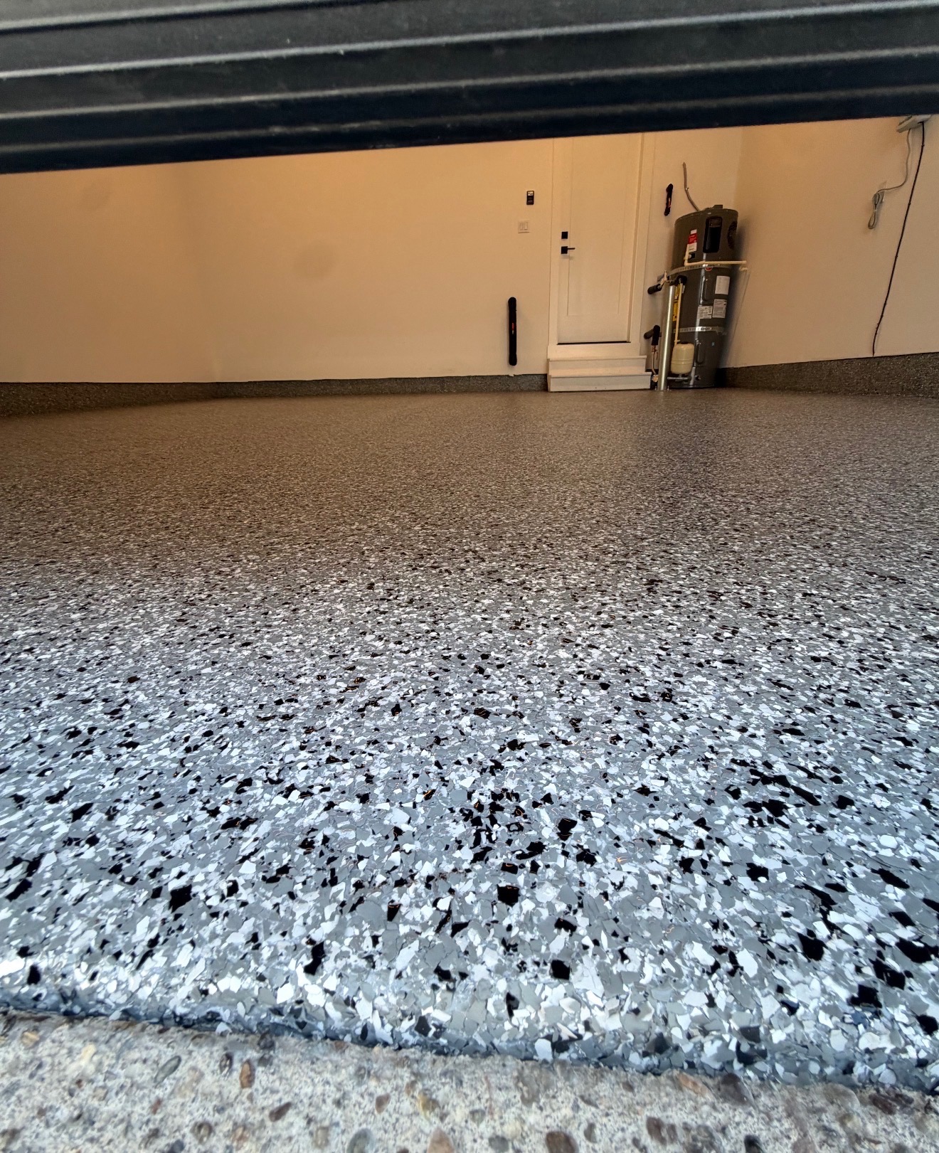 Gray flake epoxy garage floor with water heater and door view